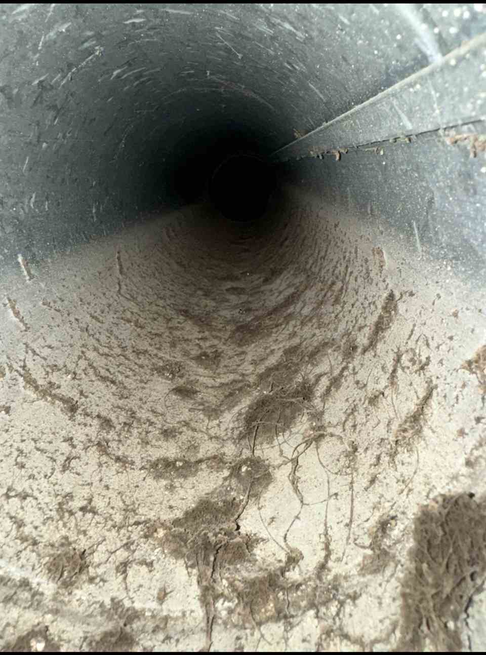 Dust and debris inside a metal air duct before cleaning in Dallas, TX